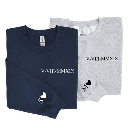 May include: A navy blue sweatshirt and a light gray sweatshirt, each featuring the Roman numeral date V-VIII-MMXIX printed on the chest. The navy sweatshirt has a white letter S and a heart on the sleeve, while the gray one has a black M and heart.