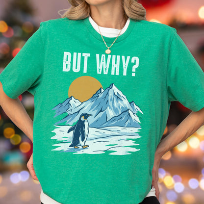 May include: Green t-shirt with the phrase "BUT WHY?" in white block letters. The shirt features a graphic of a penguin standing in front of snow-capped mountains and a yellow sun. The penguin is black and white.