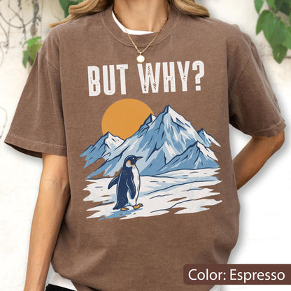 May include: Espresso-colored t-shirt featuring a graphic of a penguin standing in front of snow-covered mountains and a setting sun. The text "BUT WHY?" is printed above the graphic in white.