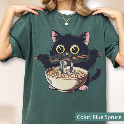 May include: Blue spruce t-shirt featuring a cartoon black cat eating ramen noodles with chopsticks. The cat has large yellow eyes and pink inner ears. The ramen bowl is white with a brown rim. The text "Color: Blue Spruce" is at the bottom.