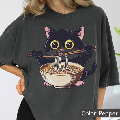 May include: Pepper-colored t-shirt featuring a cartoon black cat eating ramen noodles with chopsticks. The cat has large yellow eyes and pink ears and paws. The ramen bowl is beige with brown noodles and green toppings. The text "Color: Pepper" is at the bottom.