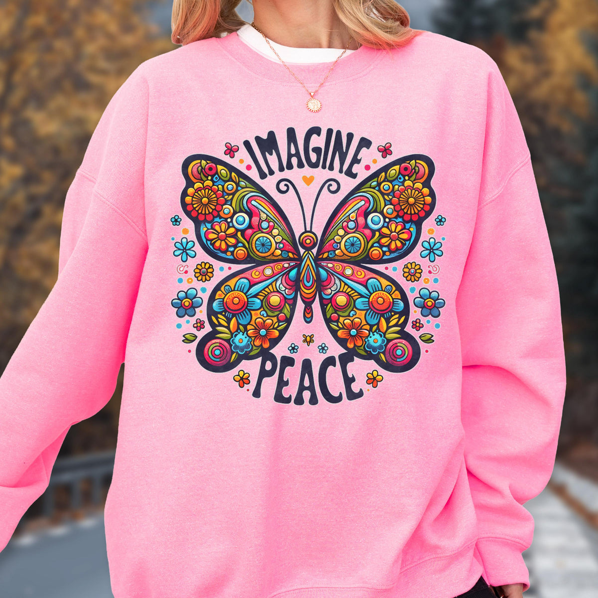 May include: Pink sweatshirt featuring a colorful butterfly design with the words "IMAGINE PEACE". The butterfly is adorned with flowers in shades of blue, orange, yellow, and green. The sweatshirt has a crew neck and long sleeves.