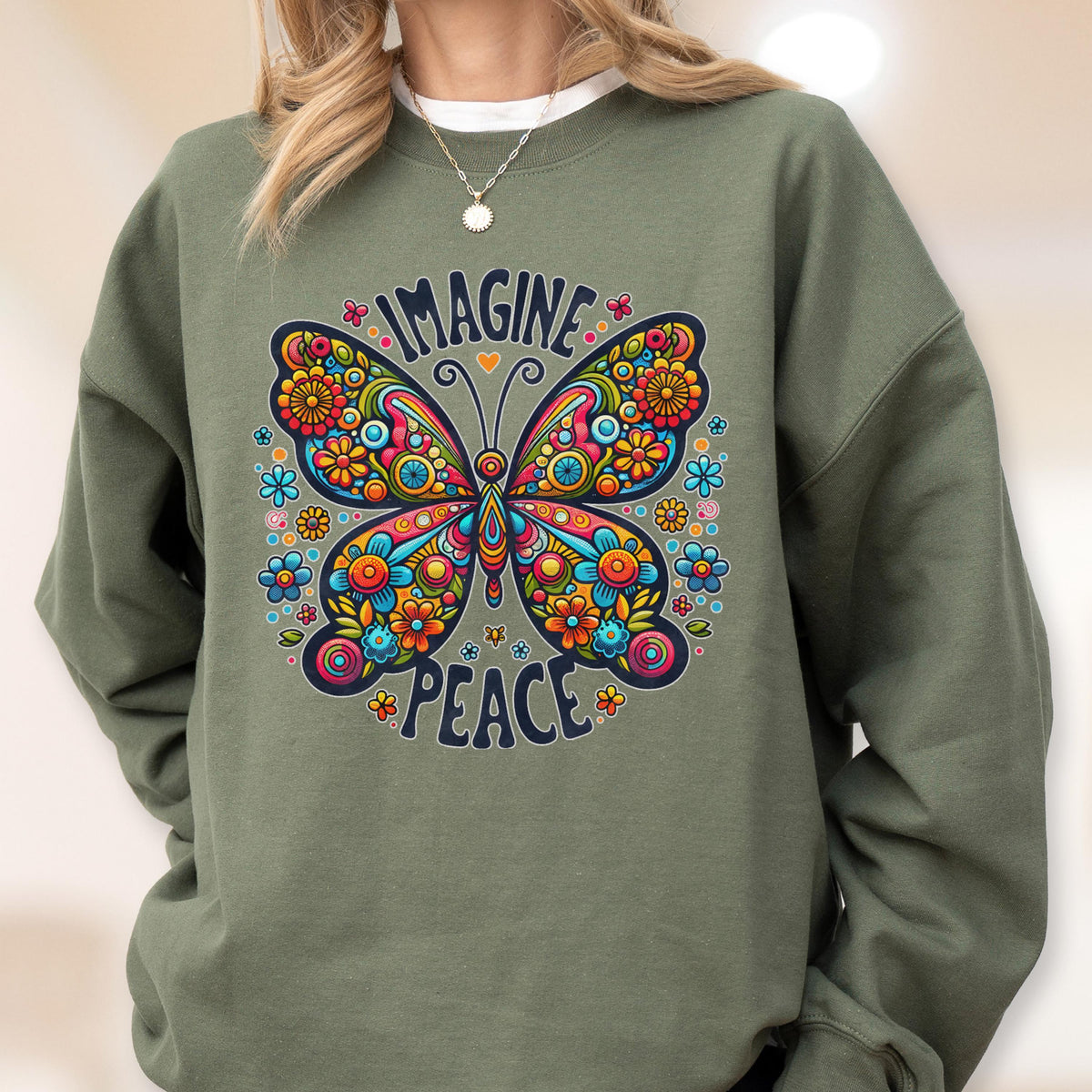 May include: An olive green sweatshirt featuring a colorful butterfly design. The butterfly has intricate floral patterns in shades of blue, orange, yellow, and pink. The words "IMAGINE PEACE" are arched above and below the butterfly.
