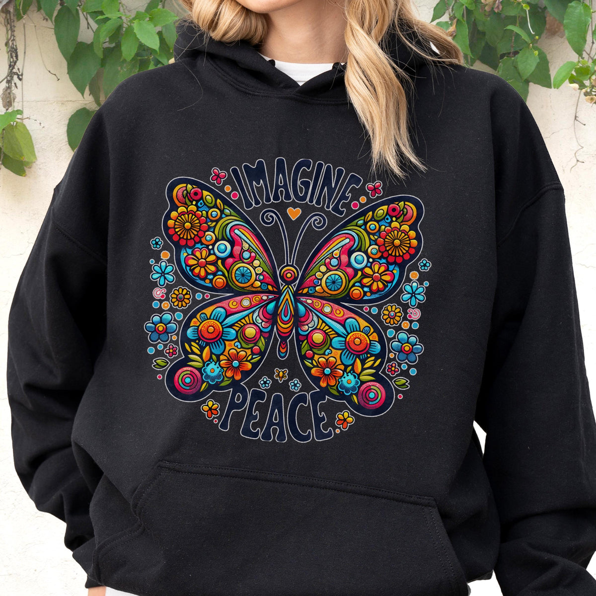 May include: Black hoodie featuring a colorful butterfly design with the words "IMAGINE PEACE". The butterfly is adorned with flowers in shades of orange, blue, yellow, and pink. The hoodie has a drawstring hood and a kangaroo pocket.