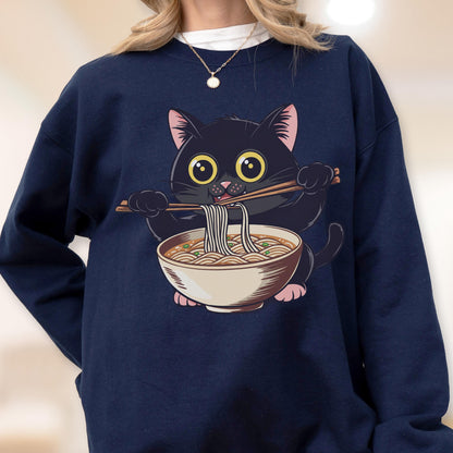 May include: Navy blue sweatshirt featuring a cartoon black cat eating ramen noodles with chopsticks. The cat has large yellow eyes and pink ears and paws. The ramen bowl is beige with brown broth and noodles.