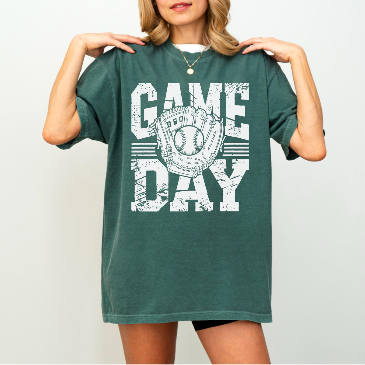 May include: Green t-shirt with the words "GAME DAY" in white block letters. A baseball glove and ball graphic is centered on the shirt. The shirt has short sleeves and a relaxed fit.