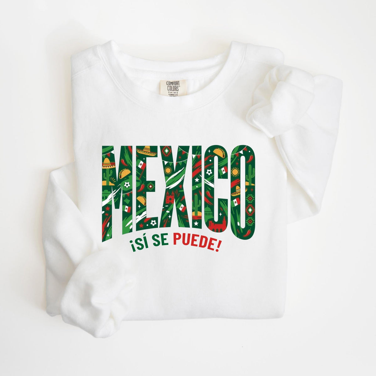 May include: White sweatshirt with the word "MEXICO" in large, green and red letters filled with Mexican-themed icons. Below the word "MEXICO" is the phrase "¡Sí se puede!" in red.