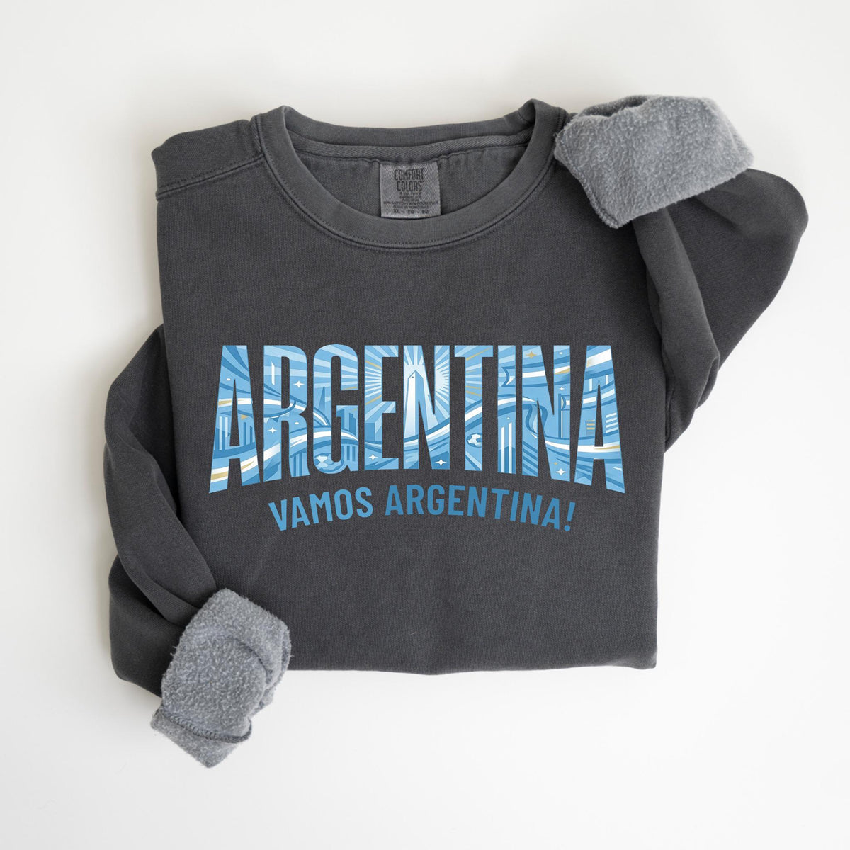 May include: Dark gray sweatshirt with the word "ARGENTINA" in blue and white block letters. Below the word is the phrase "VAMOS ARGENTINA!" in blue. The sweatshirt has gray fleece lining the cuffs.