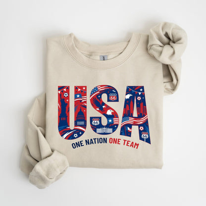 May include: A beige sweatshirt with the word "USA" in red, white, and blue, filled with American landmarks and Route 66 signs. The text "ONE NATION ONE TEAM" is below the word "USA".