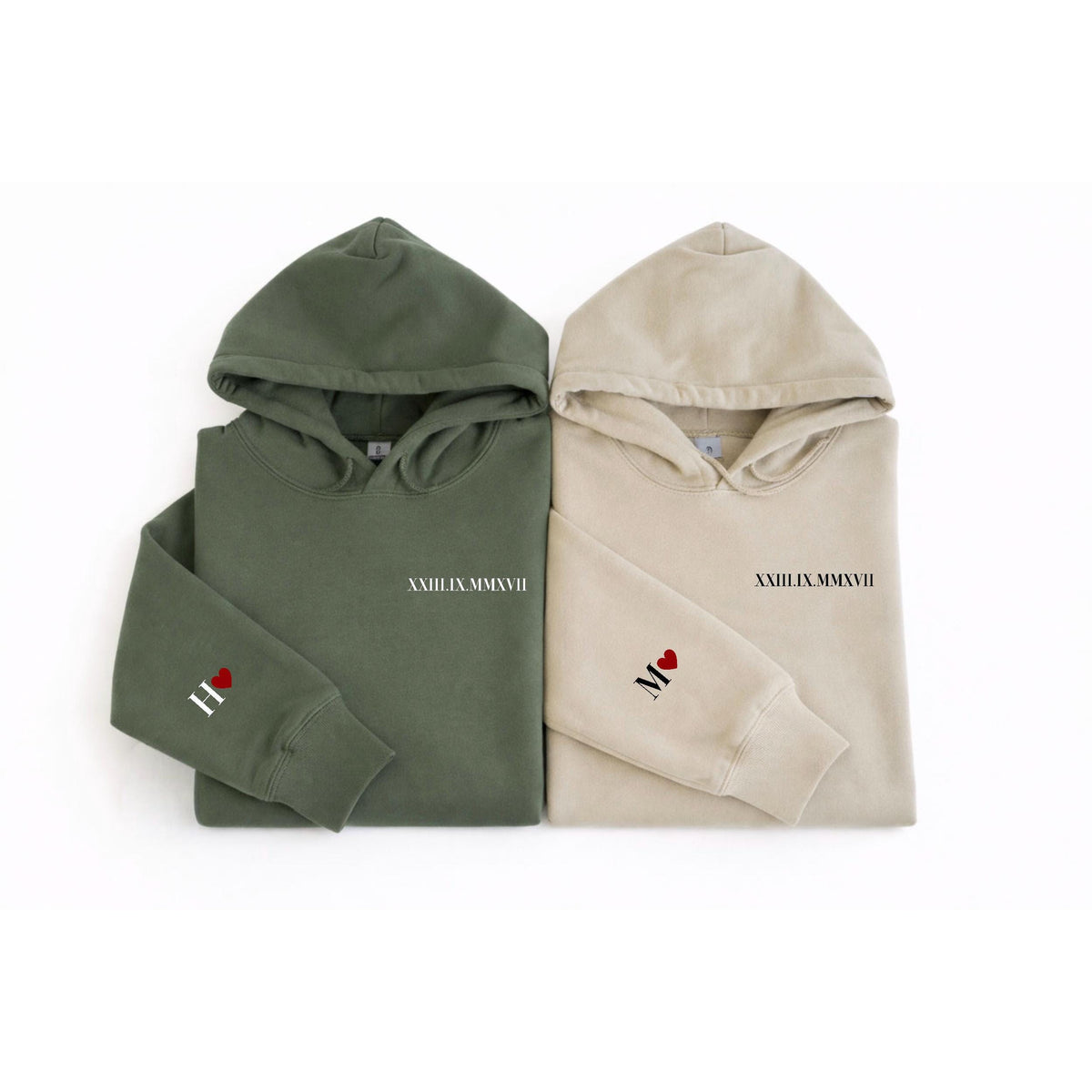 May include: Two hooded sweatshirts, one olive green and one beige. Each has the Roman numeral date "XXIII.MMXVII" printed on the chest. The left sleeve of the green sweatshirt has a red heart and the letter "H". The beige sweatshirt has a red heart and the letter "M".