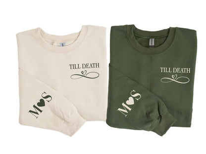 May include: Two long-sleeved sweatshirts, one cream and one olive green, are displayed. Each has the phrase "Till Death" with a heart-shaped infinity symbol. The left sleeve of each shirt has initials and a heart.