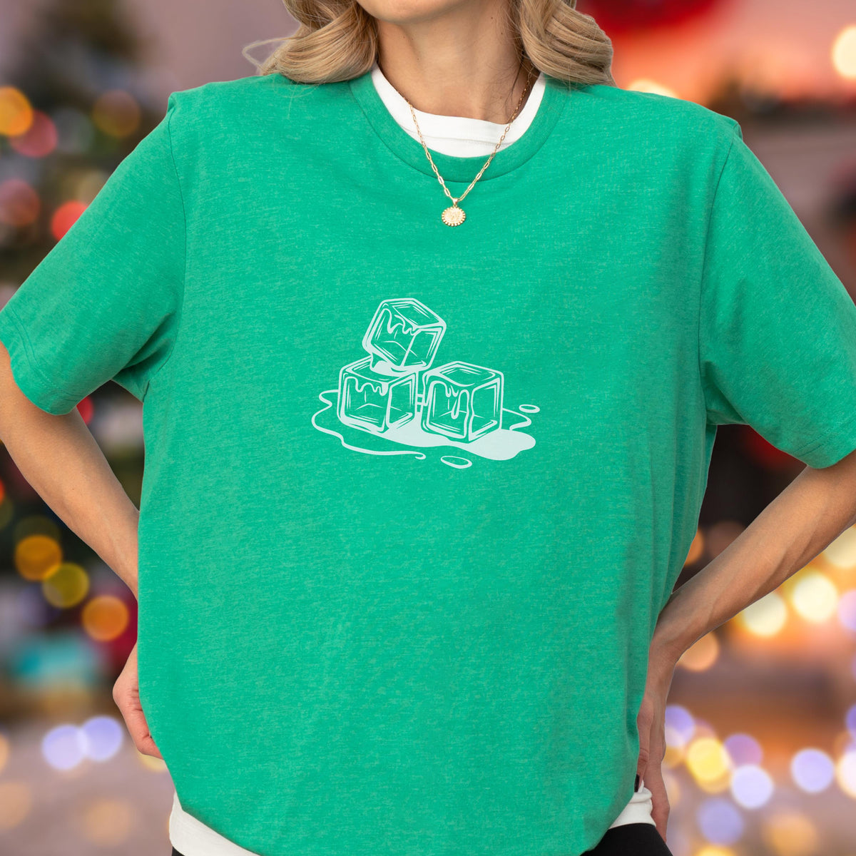 May include: A green t-shirt with a white graphic of three ice cubes melting. The shirt has short sleeves and a crew neck, with a white undershirt visible. The graphic is centered on the chest.