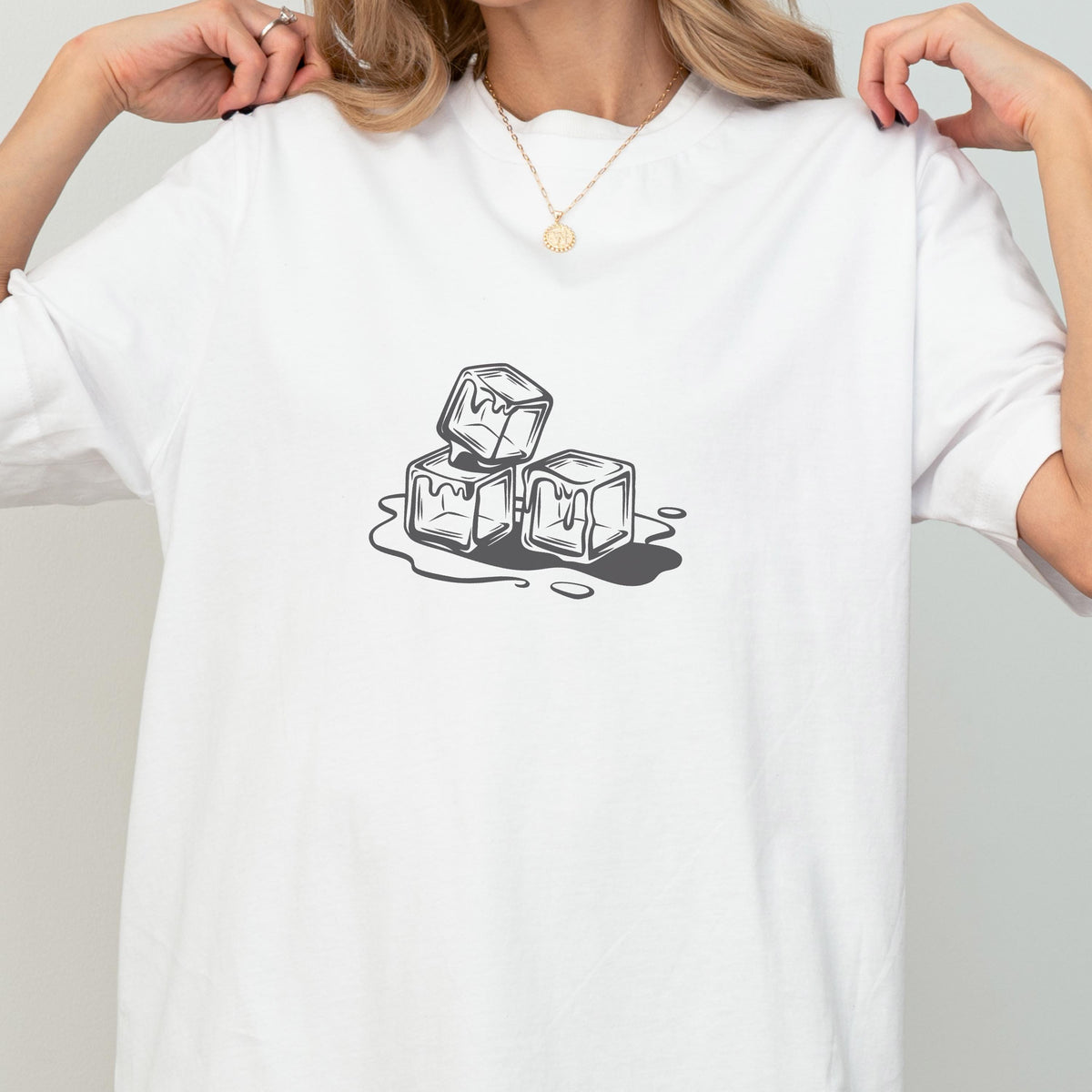 May include: White t-shirt featuring a graphic of three melting ice cubes in shades of gray. The design is a simple illustration, with the ice cubes stacked and the water forming around them. The shirt is a casual, everyday wear item.