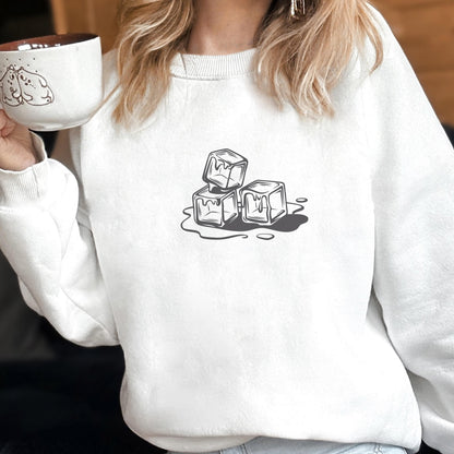 May include: White sweatshirt featuring a black and white graphic of three melting ice cubes. The design is centered on the front of the long-sleeved crew neck top. The sweatshirt is made of a soft material.