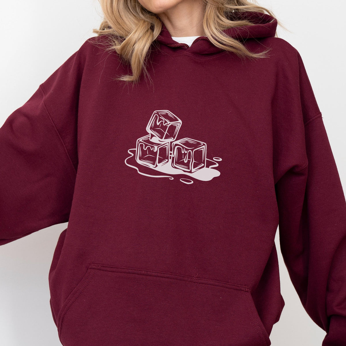 May include: Burgundy hoodie with a white graphic of three melting ice cubes. The design is a simple line drawing, creating a minimalist aesthetic. The hoodie has a drawstring hood and a front pocket.