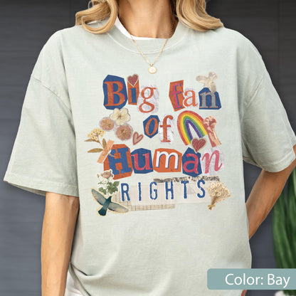 May include: A light green t-shirt with the text "Big Fan of Human Rights" in a collage style. The design includes a rainbow, hearts, and floral elements. The shirt is a relaxed fit.