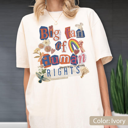 May include: Ivory-colored t-shirt with the text "Big Fan of Human Rights" in a collage style. The design includes a rainbow, hearts, and floral elements. The shirt is a relaxed fit.