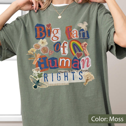 May include: Moss green t-shirt with a collage design. The design includes the text "Big fan of Human Rights" in a mix of fonts and colors, along with illustrations of a rainbow, flowers, and a raised fist.