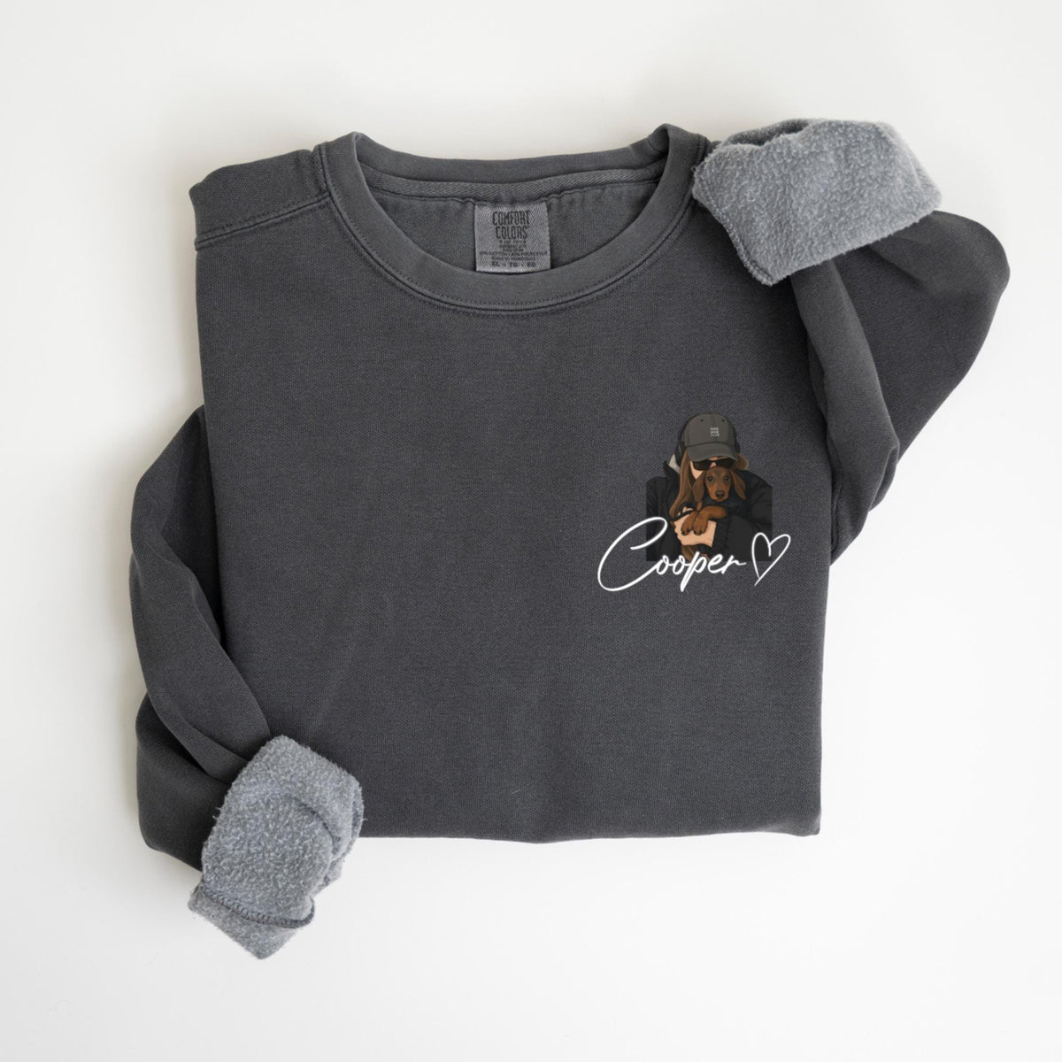 May include: Dark gray sweatshirt with a dog graphic wearing a hat and sunglasses. The name "Cooper" is written in cursive below the graphic, with a heart symbol. The sleeves have a soft, gray lining.