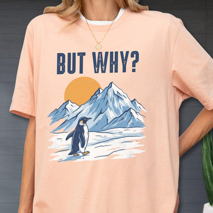 May include: Peach-colored t-shirt with a graphic featuring a penguin, mountains, and a sun. The text "BUT WHY?" is printed above the illustration. The shirt has a white collar.