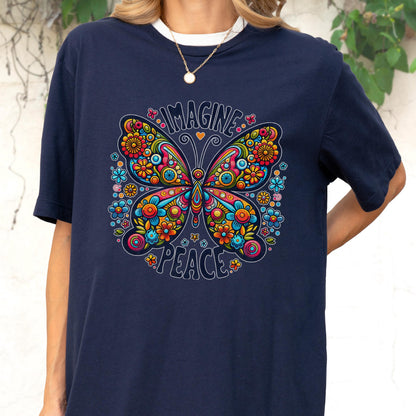 May include: A navy blue t-shirt featuring a large, colorful butterfly graphic with intricate floral patterns in shades of red, orange, yellow, blue, and pink. The text "IMAGINE" is printed above the butterfly and "PEACE" is printed below it.