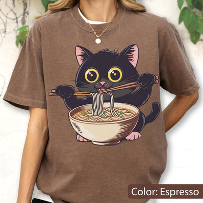 May include: Espresso-colored t-shirt featuring a cartoon black cat enjoying ramen noodles. The cat, with large yellow eyes, holds chopsticks. The ramen bowl is beige with a white rim. The text "Color: Espresso" is at the bottom.