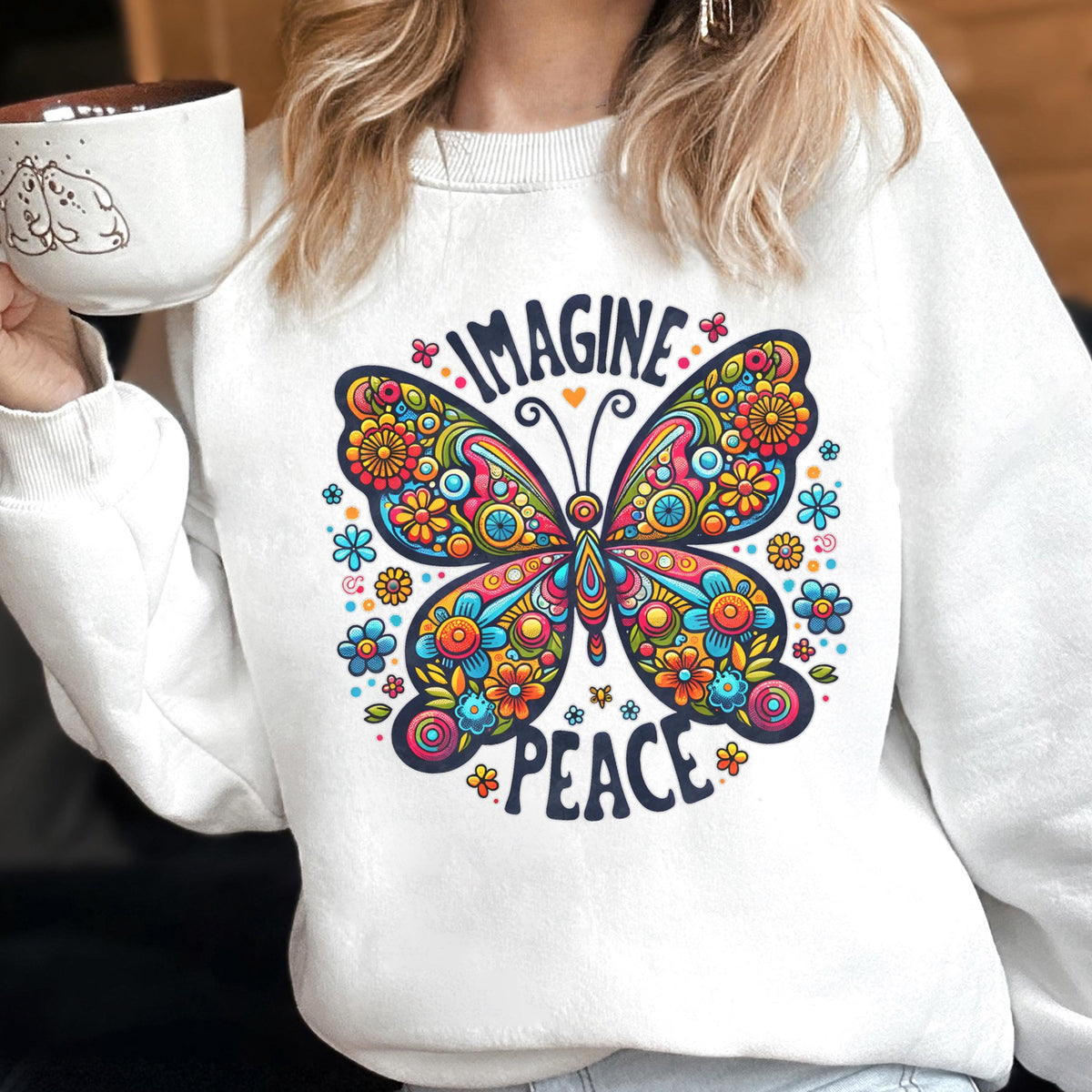 May include: White sweatshirt featuring a colorful butterfly design with the words "IMAGINE PEACE". The butterfly is filled with flowers in shades of blue, orange, yellow, and pink. The sweatshirt is a crew neck style.