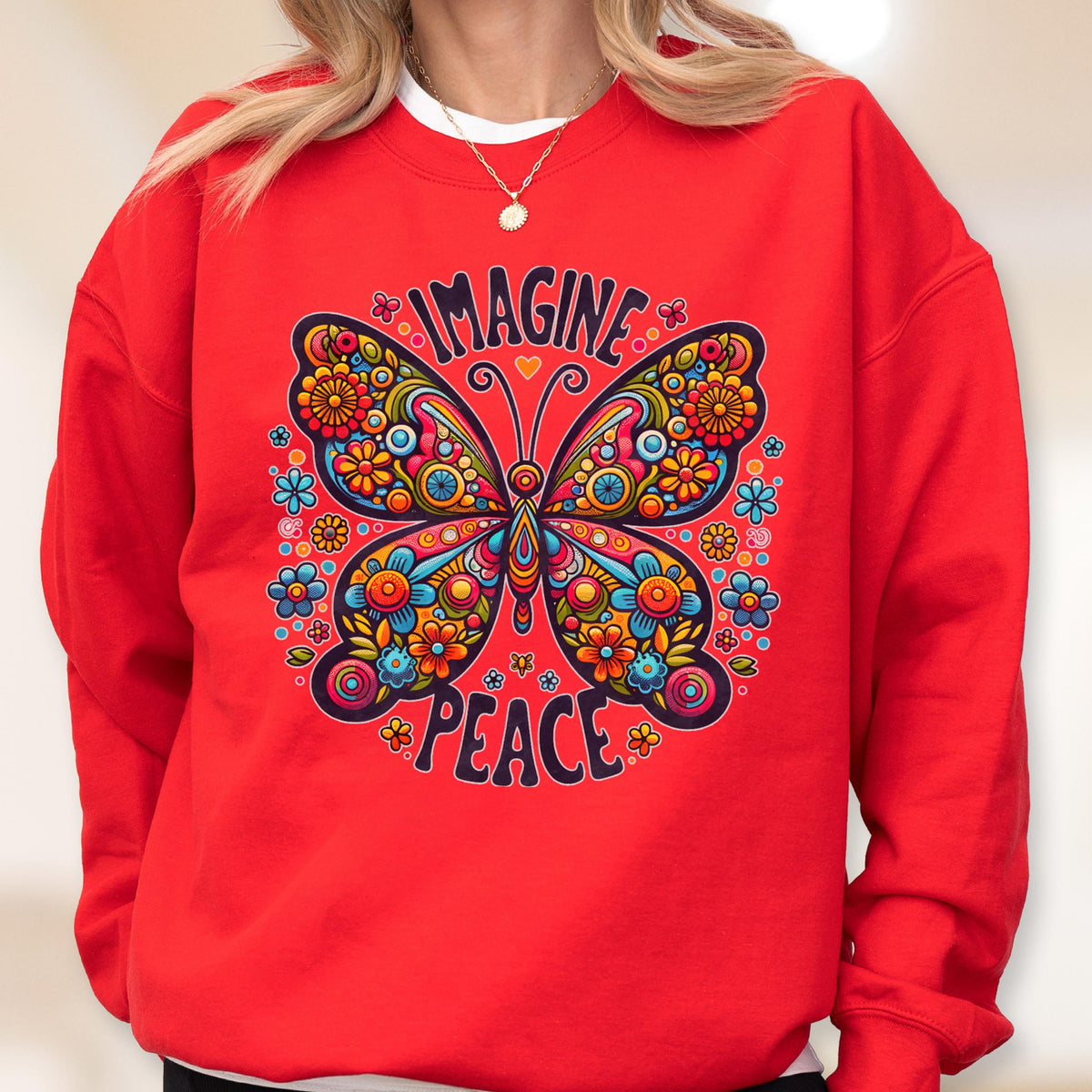May include: A red sweatshirt featuring a colorful butterfly design with the words "IMAGINE" and "PEACE". The butterfly is decorated with flowers in shades of blue, orange, yellow, and pink. The sweatshirt has a crew neck.