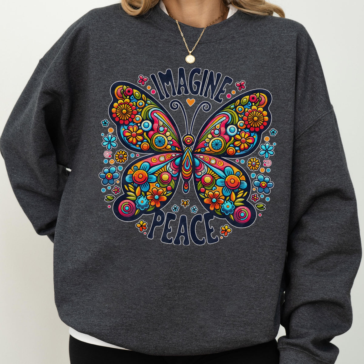 May include: A dark gray sweatshirt featuring a colorful butterfly design with the words "IMAGINE PEACE". The butterfly is decorated with flowers in shades of blue, orange, yellow, and pink. The sweatshirt is a casual style.
