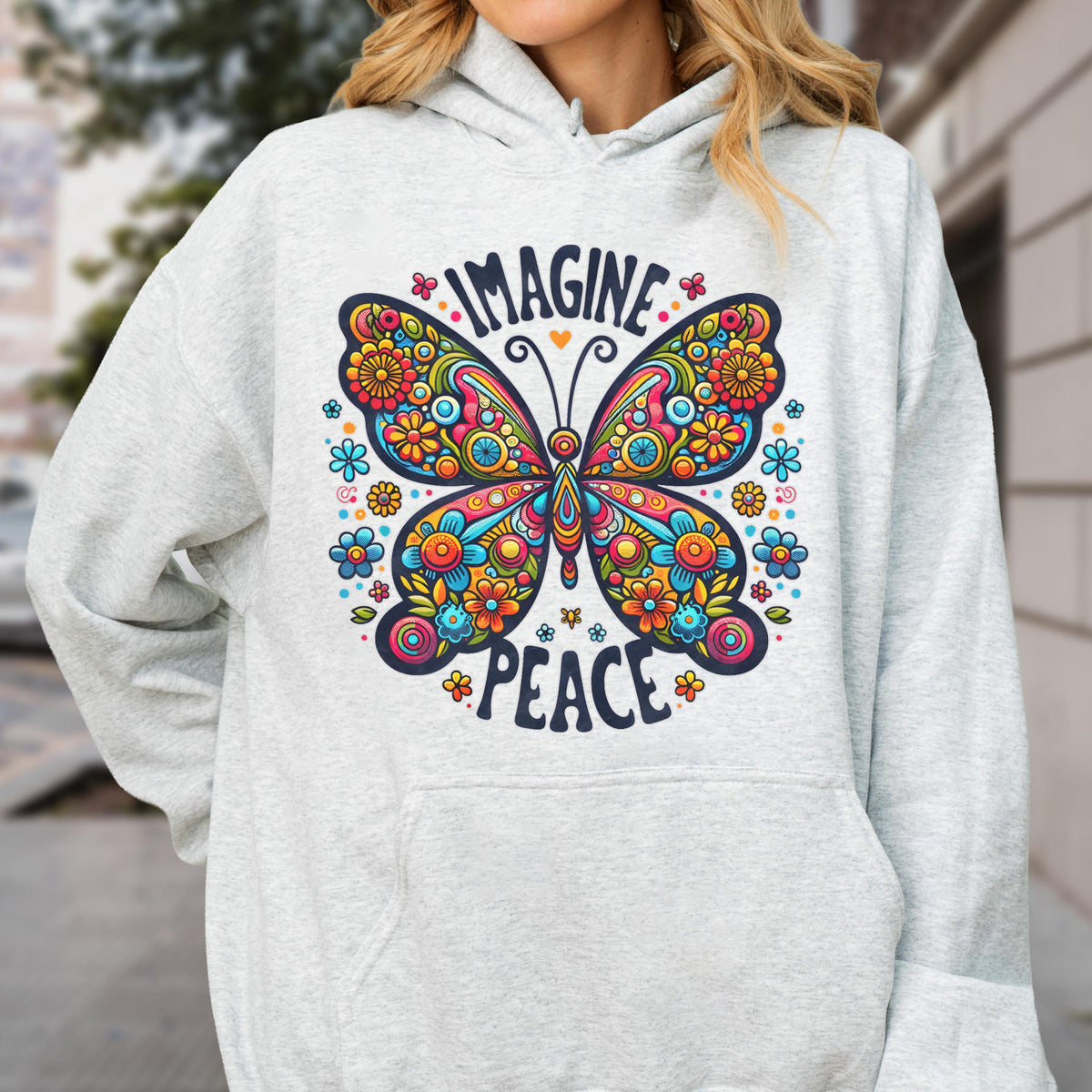 May include: A light gray hoodie featuring a colorful butterfly design. The butterfly is adorned with flowers and the words "IMAGINE PEACE" are above and below the butterfly. The hoodie has a front pocket and a hood.