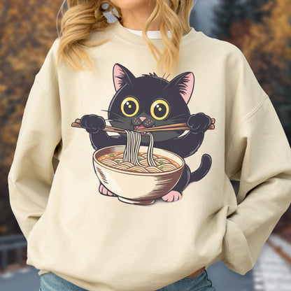 May include: Beige sweatshirt featuring a cartoon black cat holding chopsticks and a bowl of ramen. The cat has large yellow eyes and pink paws. The ramen bowl is beige with brown accents. The sweatshirt is a neutral color.