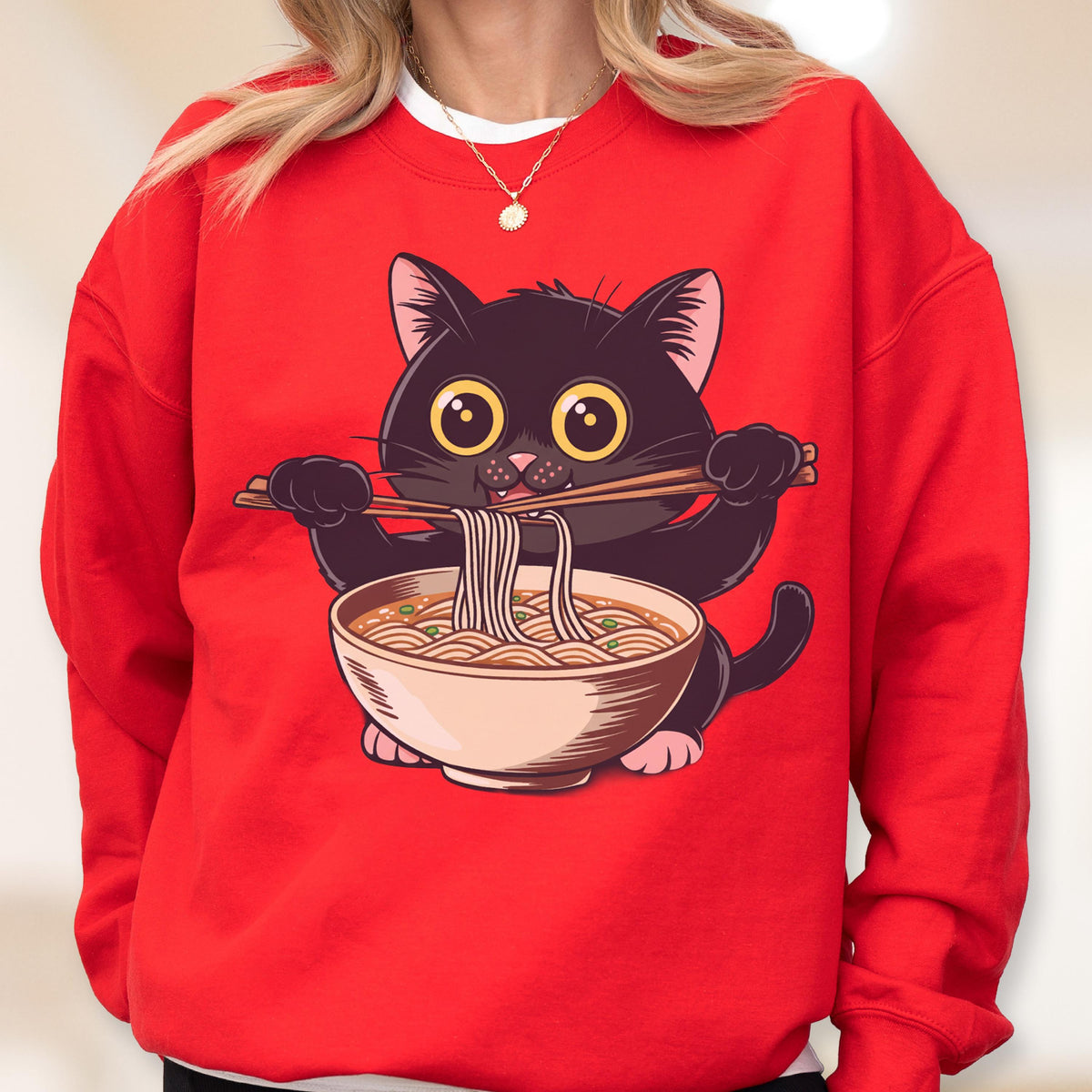 May include: Red sweatshirt featuring a cartoon black cat holding chopsticks with noodles from a bowl. The cat has large yellow eyes and is centered on the front of the sweatshirt. The design is a playful illustration.