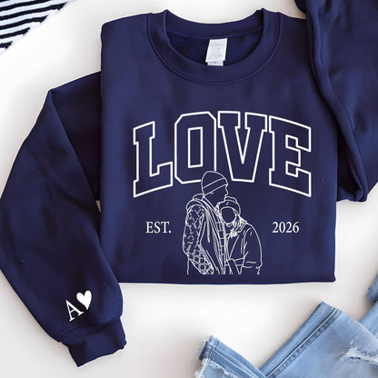 May include: Navy blue sweatshirt with the word "LOVE" in white block letters. Below the word "LOVE" is a line drawing of a couple and the text "EST. 2026". The left sleeve has a white heart and the letter "A".
