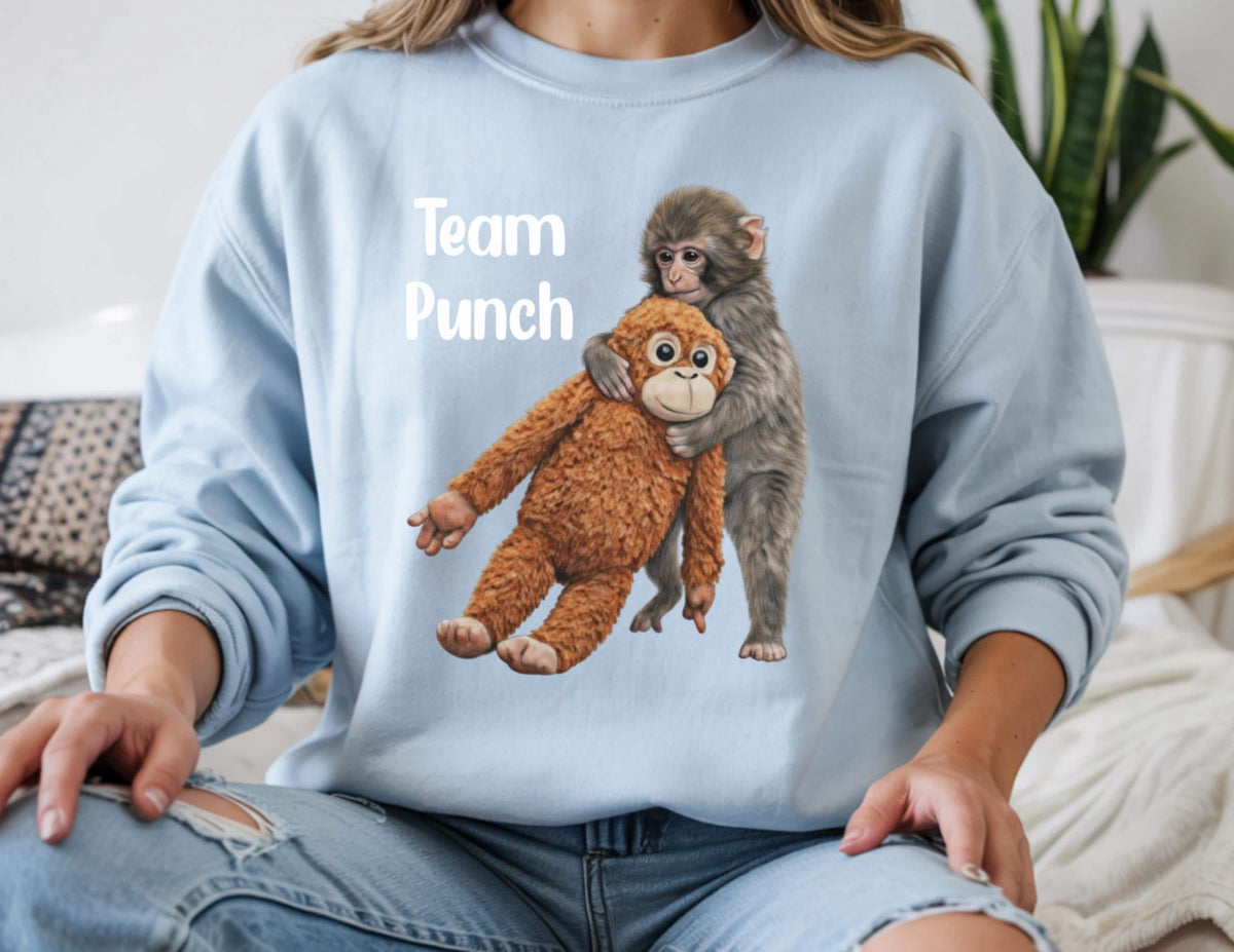 May include: A light blue sweatshirt with the text "Team Punch" in white. The graphic features a brown stuffed monkey being hugged by a gray monkey. The sweatshirt is made of a soft material.