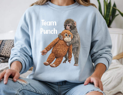 May include: A light blue sweatshirt with the text "Team Punch" in white. The graphic features a brown stuffed monkey being hugged by a gray monkey. The sweatshirt is made of a soft material.