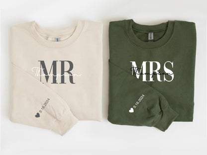 May include: Two crewneck sweatshirts, one beige and one olive green. The beige sweatshirt says "MR Thompson" in dark gray and script font. The olive green sweatshirt says "MRS Thompson" in white. Both sleeves have the date "9.16.2024" and a heart.