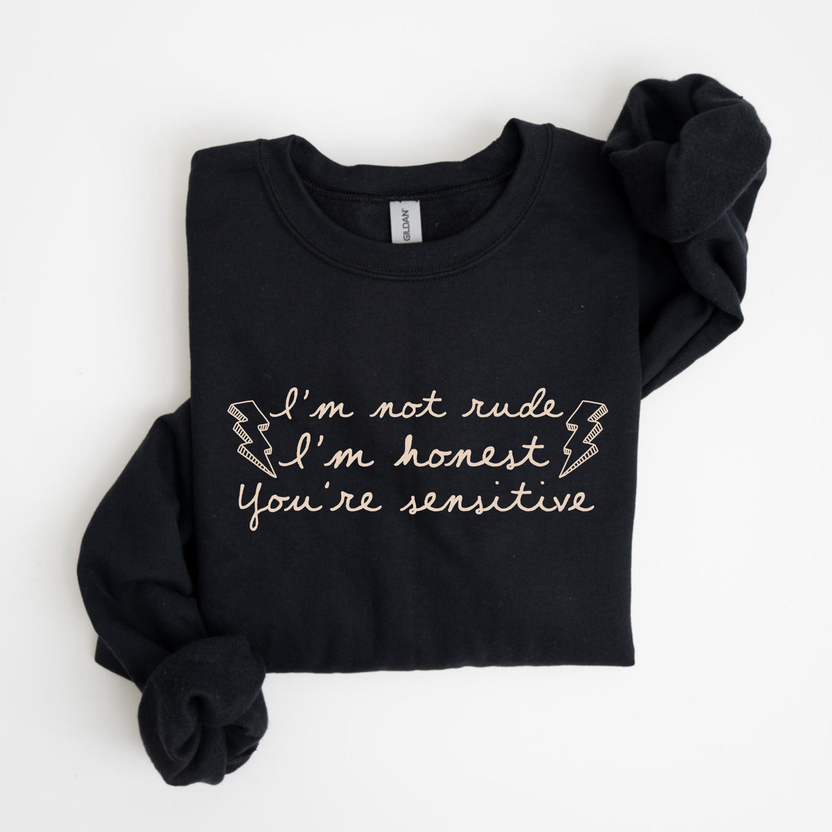 May include: Black crew neck sweatshirt with the text "I'm not rude, I'm honest, You're sensitive" in a light pink script. The sweatshirt has long sleeves and is folded neatly. The text includes lightning bolt graphics.