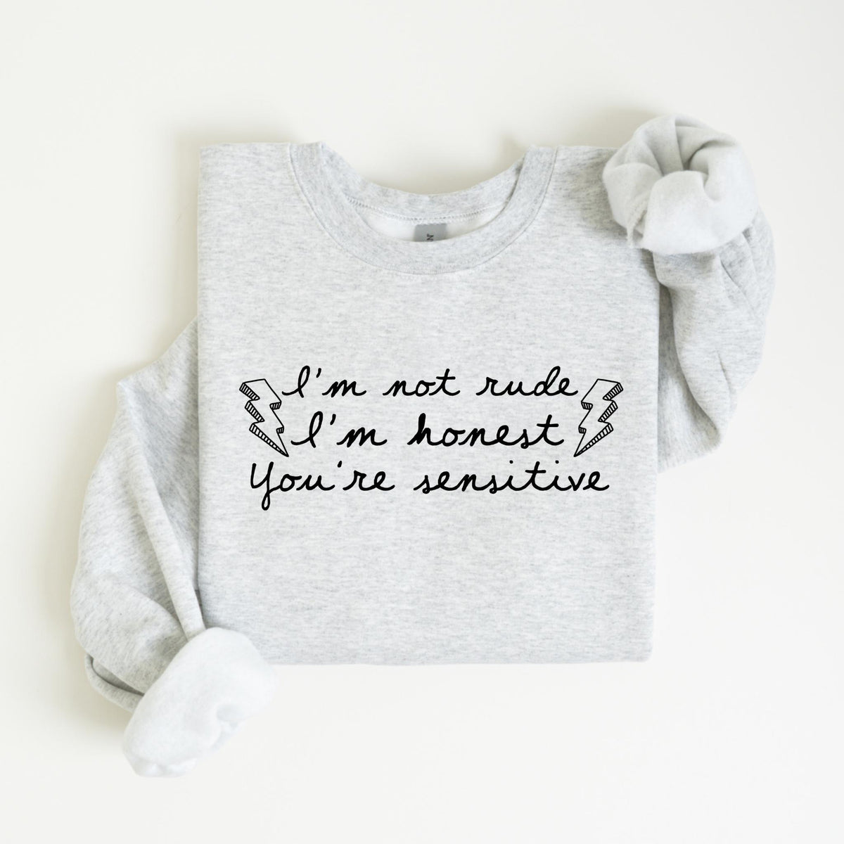 May include: A light gray sweatshirt with the text "I'm not rude, I'm honest, You're sensitive" in black script. The design includes two lightning bolt graphics. The sweatshirt has long sleeves and a crew neck.