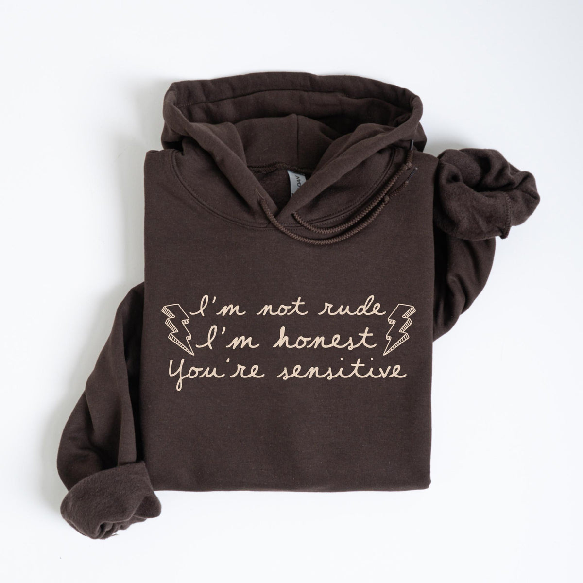 May include: A dark brown hoodie with the text "I'm not rude, I'm honest, You're sensitive" in a light beige script. The hoodie is folded neatly, showcasing the hood and sleeves. The text is accompanied by lightning bolt graphics.