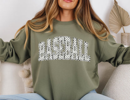 May include: An olive green sweatshirt with the word "BASEBALL" in large, white, dotted letters across the chest. The sweatshirt has long sleeves and a crew neck.