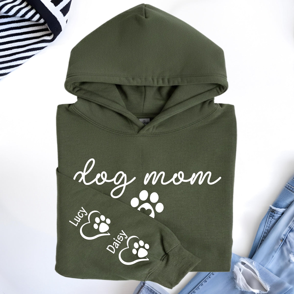 May include: An olive green hoodie with the words "dog mom" in white script. The sleeve features paw prints and the names "Lucy" and "Daisy". The hoodie is made of a soft material and has a hood.