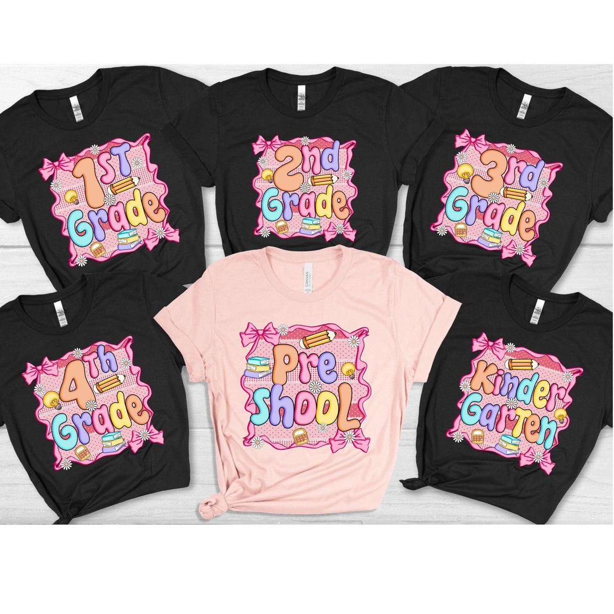 May include: A collection of black and pink t-shirts with school-themed graphics. Each shirt features a grade level, such as "1st Grade" or "Kindergarten," in colorful bubble letters, surrounded by bows, pencils, and books.