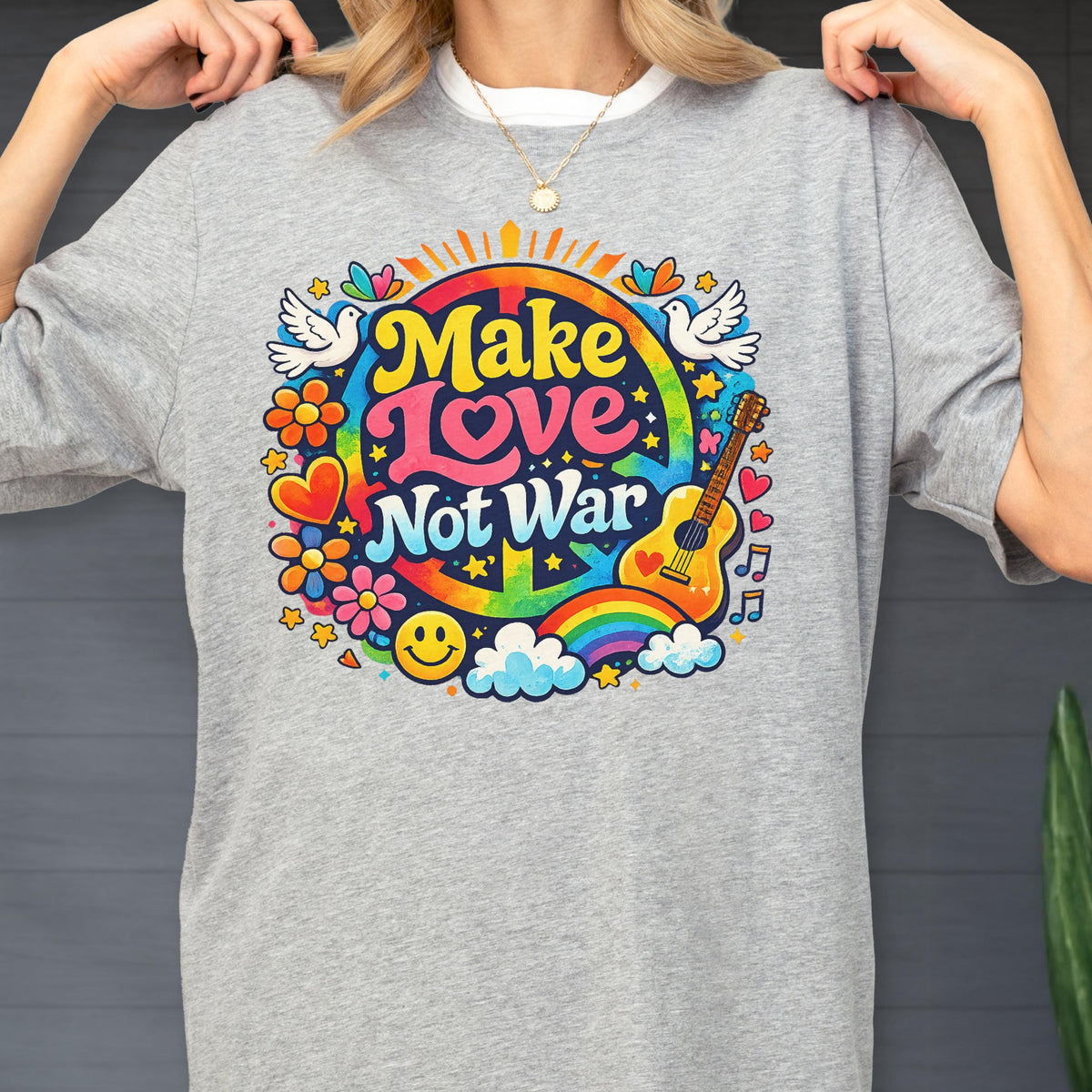 May include: A gray t-shirt with a colorful graphic that says "Make Love Not War." The design includes a peace sign, rainbow, guitar, doves, flowers, and a smiley face. The shirt is a casual, everyday wear item.