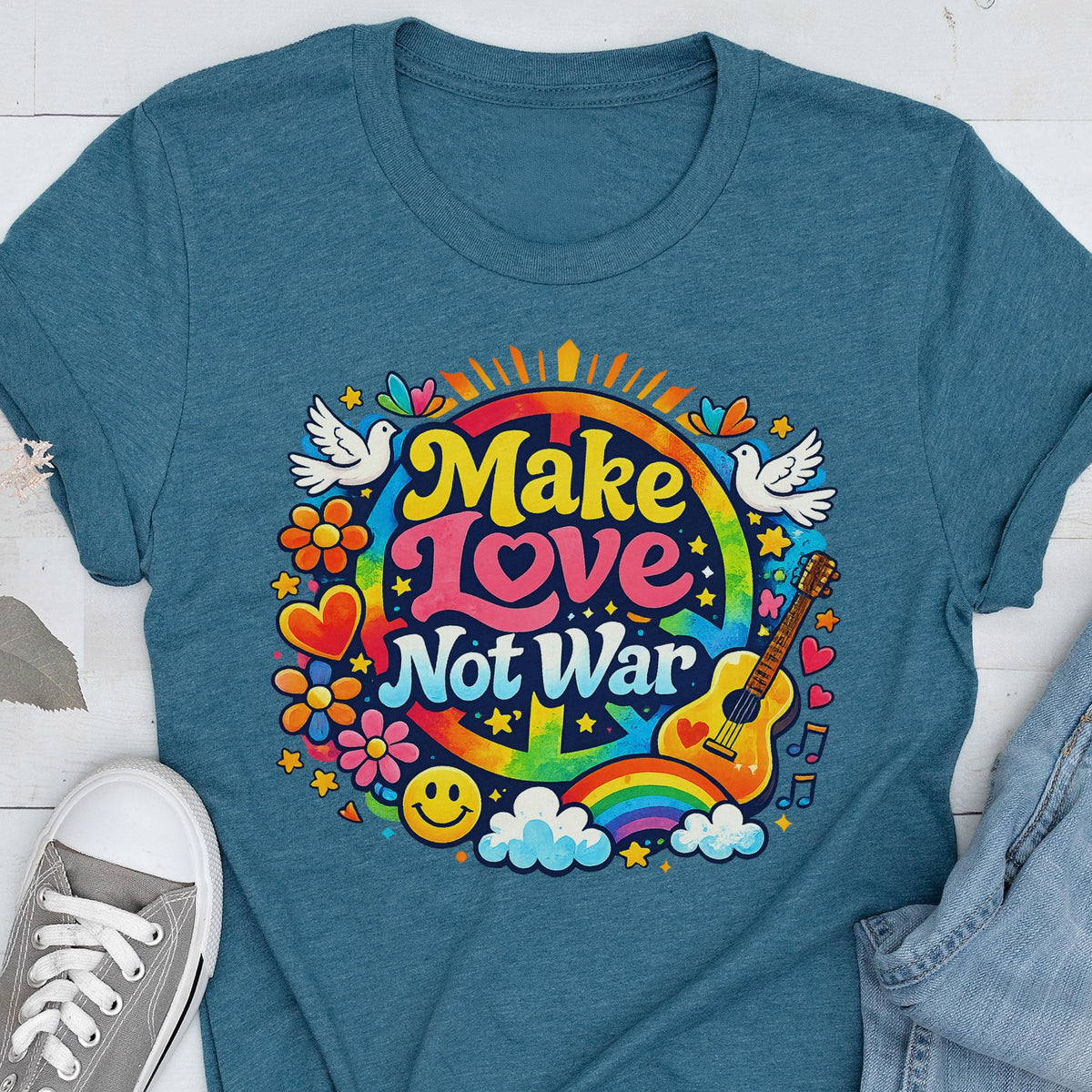 May include: Teal t-shirt with a colorful graphic that says "Make Love Not War." The design includes a peace sign, rainbow, guitar, flowers, doves, and a smiley face. The shirt is made of a soft material.