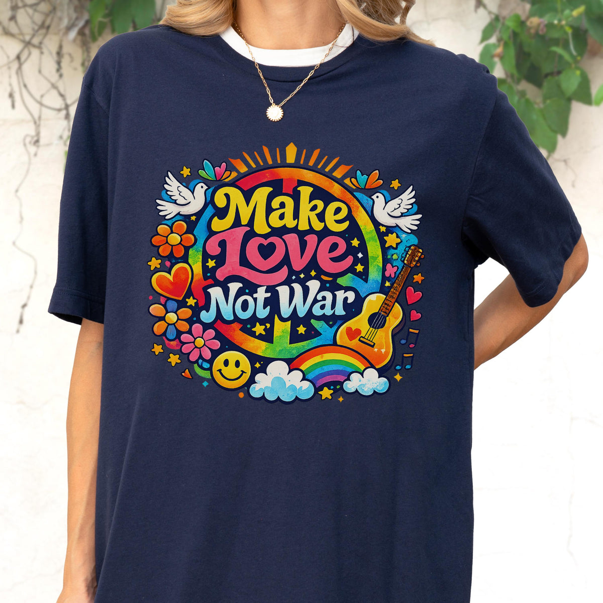 May include: Navy blue t-shirt with a colorful graphic that says "Make Love Not War." The design includes a peace sign, rainbow, guitar, flowers, and doves. The shirt has a white crew neck.