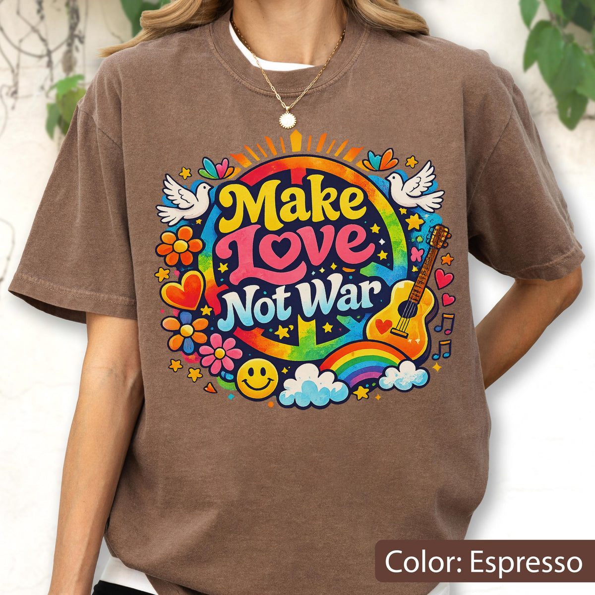 May include: Espresso-colored t-shirt with a colorful graphic that says "Make Love Not War." The design includes a peace sign, rainbow, guitar, flowers, doves, and a smiley face. The shirt is a casual, comfortable style.