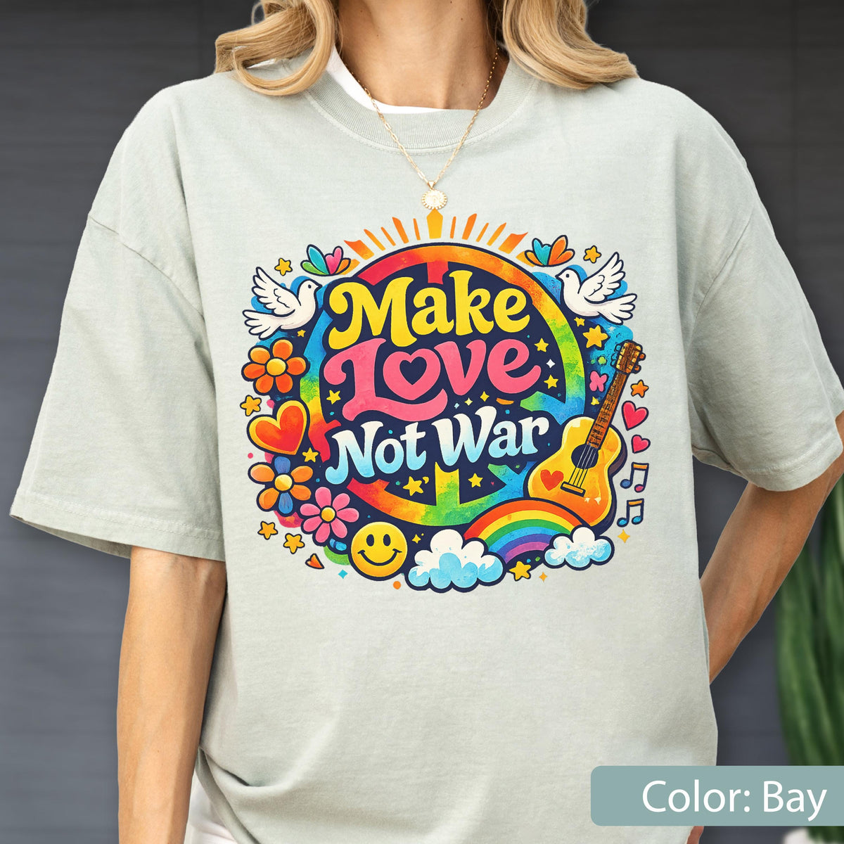 May include: A light green t-shirt with a colorful graphic that says "Make Love Not War". The design includes a peace sign, rainbow, guitar, flowers, and doves. The shirt is a relaxed fit.