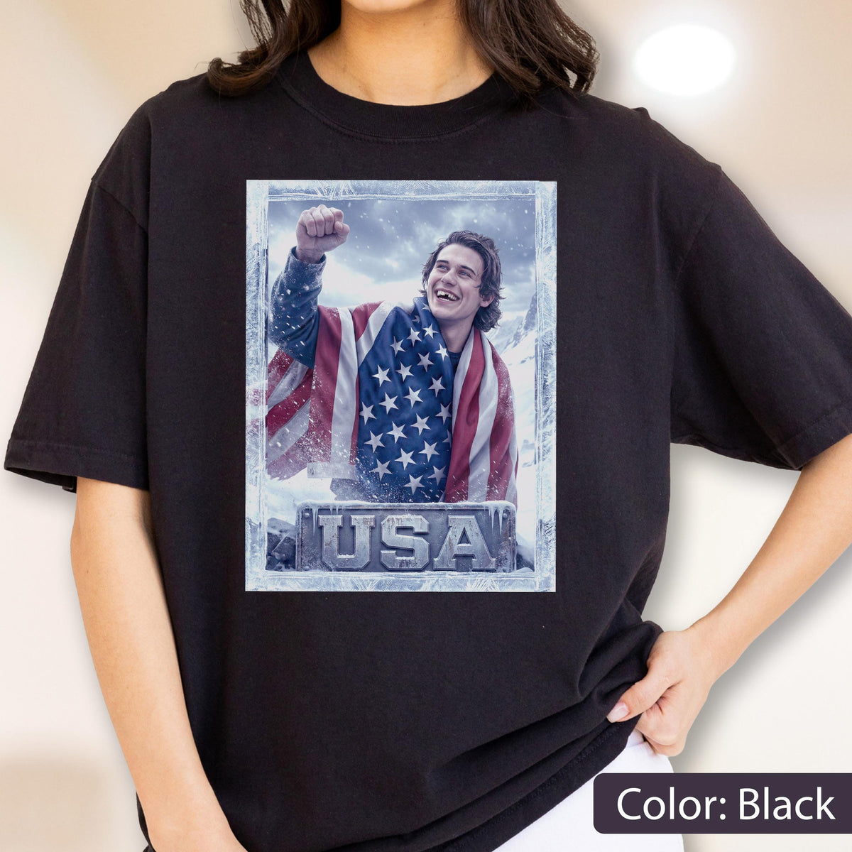May include: Black t-shirt featuring a framed graphic of a person wrapped in an American flag, with the word "USA" at the bottom. The person is smiling and raising a fist. The shirt is a solid black color.