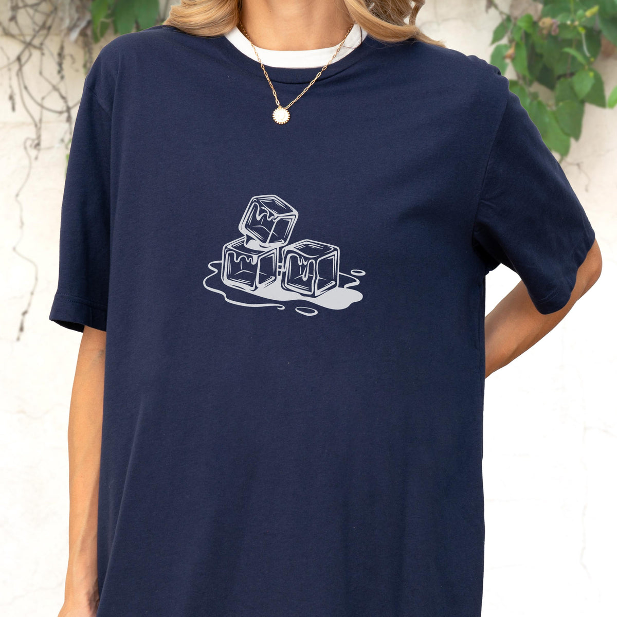 May include: Navy blue t-shirt with a white collar and a graphic of three melting ice cubes. The ice cubes are white with gray shading, and the design is centered on the shirt.