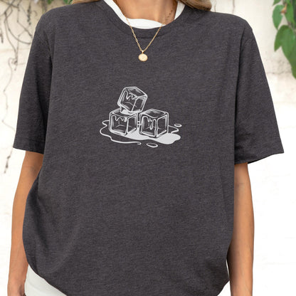 May include: Dark gray t-shirt featuring a white graphic of three melting ice cubes. The shirt has short sleeves and a crew neck. The design is centered on the chest. The shirt is made of a soft material.